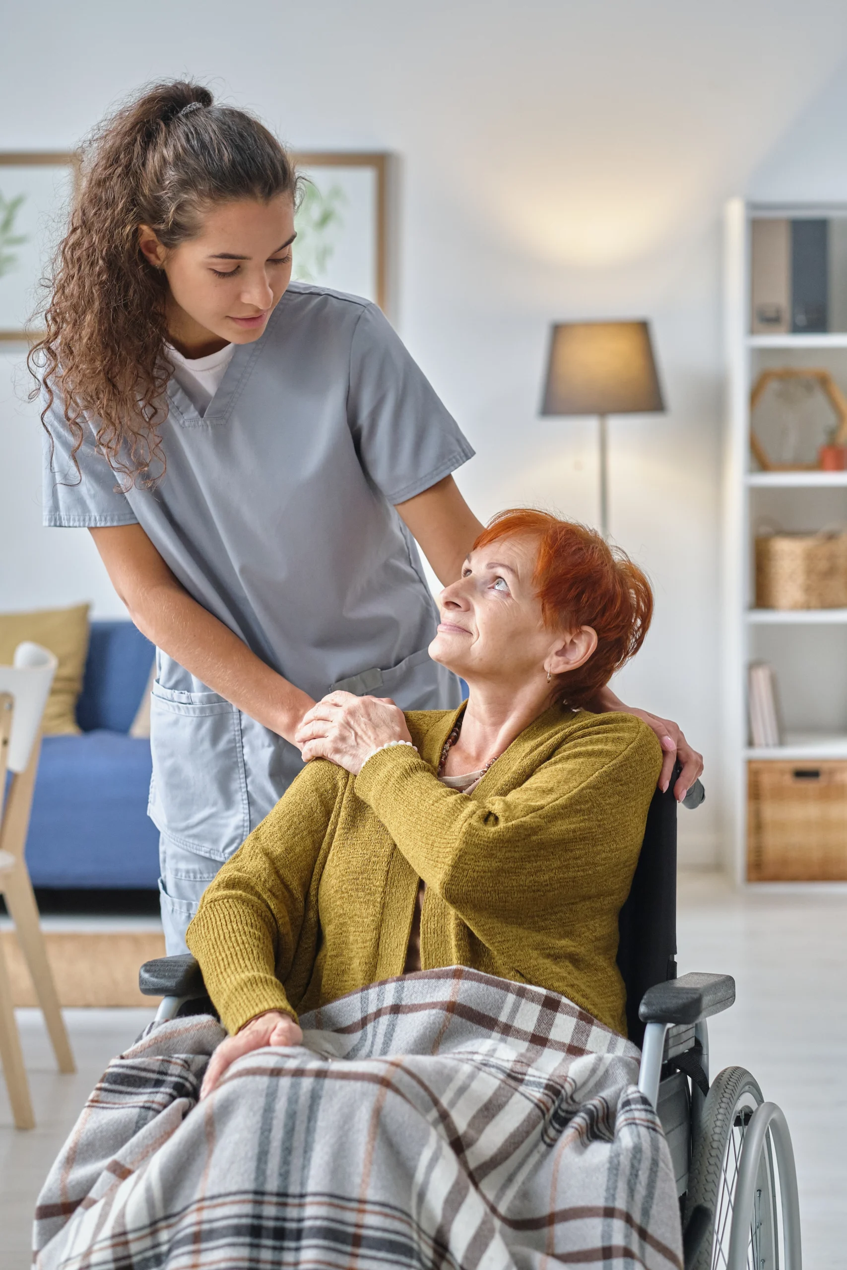 Home Care Capitol Heights MD curly haired caretaker assists elderly woman into wheelchair