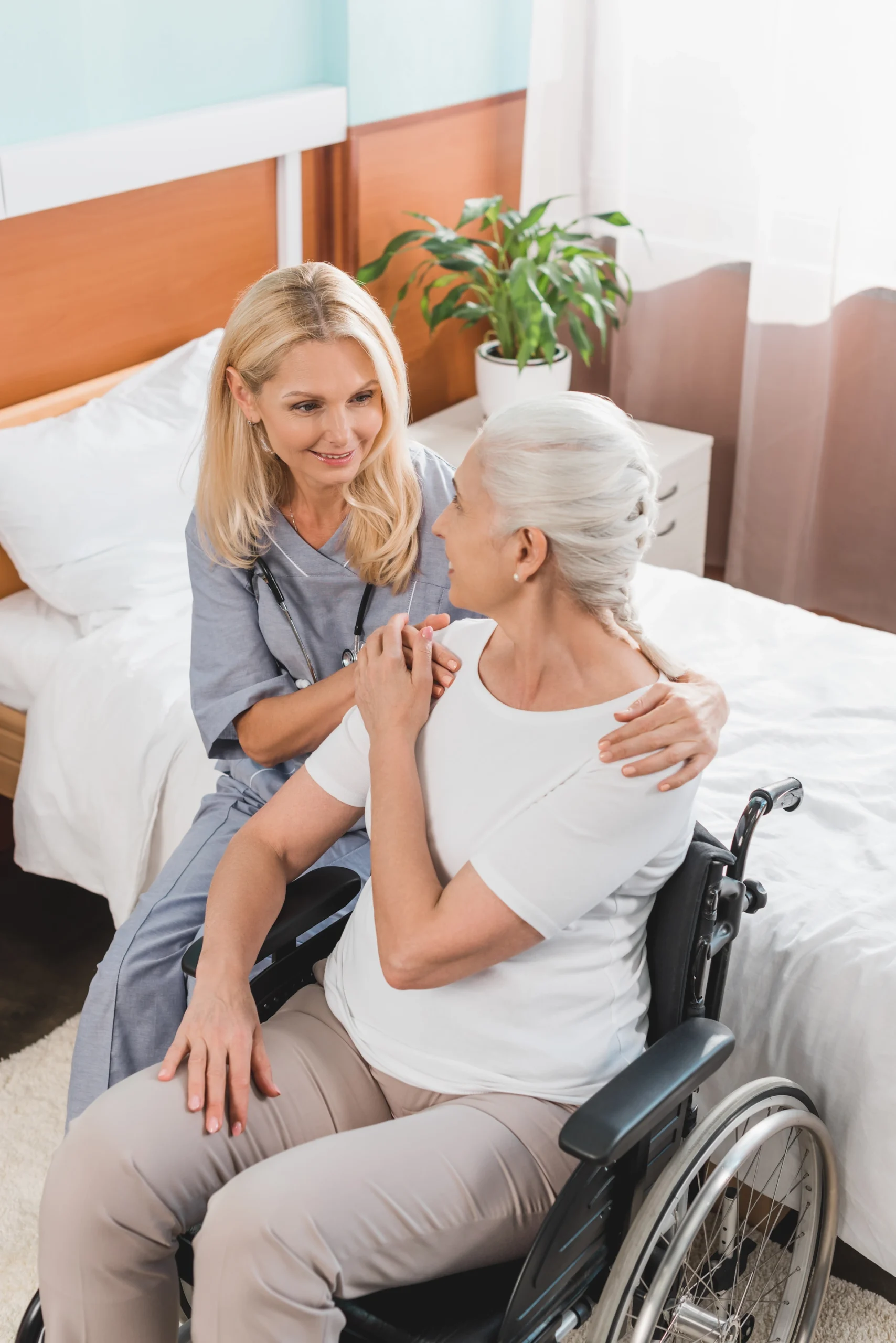 Compassionate nurse supports a senior woman in a wheelchair with comfort, dignity, and personalized care at home.